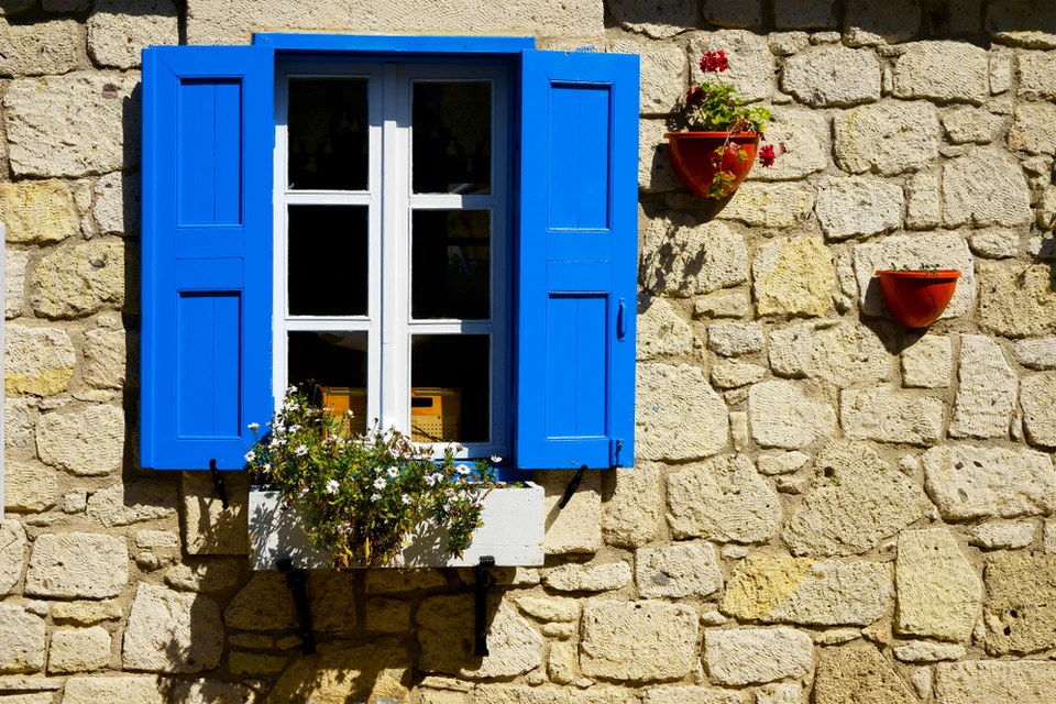 Extérieur résidentiel, ouvrier en tenue blanche appliquant de la peinture sur mur de crépi beige près d'une baie vitrée