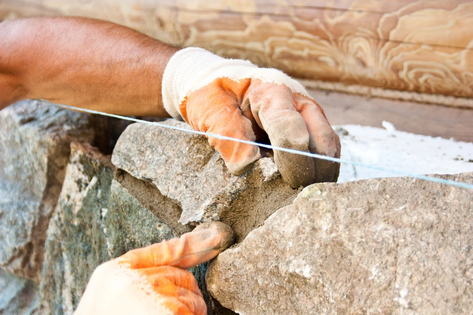 Artisan tailleur de pierre travaillant sur bloc calcaire avec ciseau à pierre et massette
