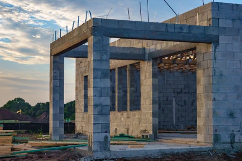 Chantier ext&eacute;rieur de ma&ccedil;onnerie avec ouvrier posant des briques rouges
