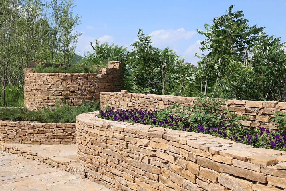 Jardin paysager en terrasses avec murets de pierres naturelles et plantations diversifiées