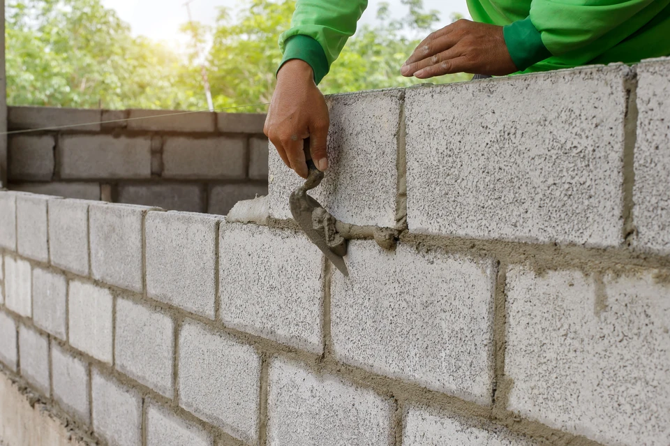 Trois professionnels de la construction en tenue de s&eacute;curit&eacute; se serrant la main sur un chantier, symbolisant le travail d'&eacute;quipe et la collaboration